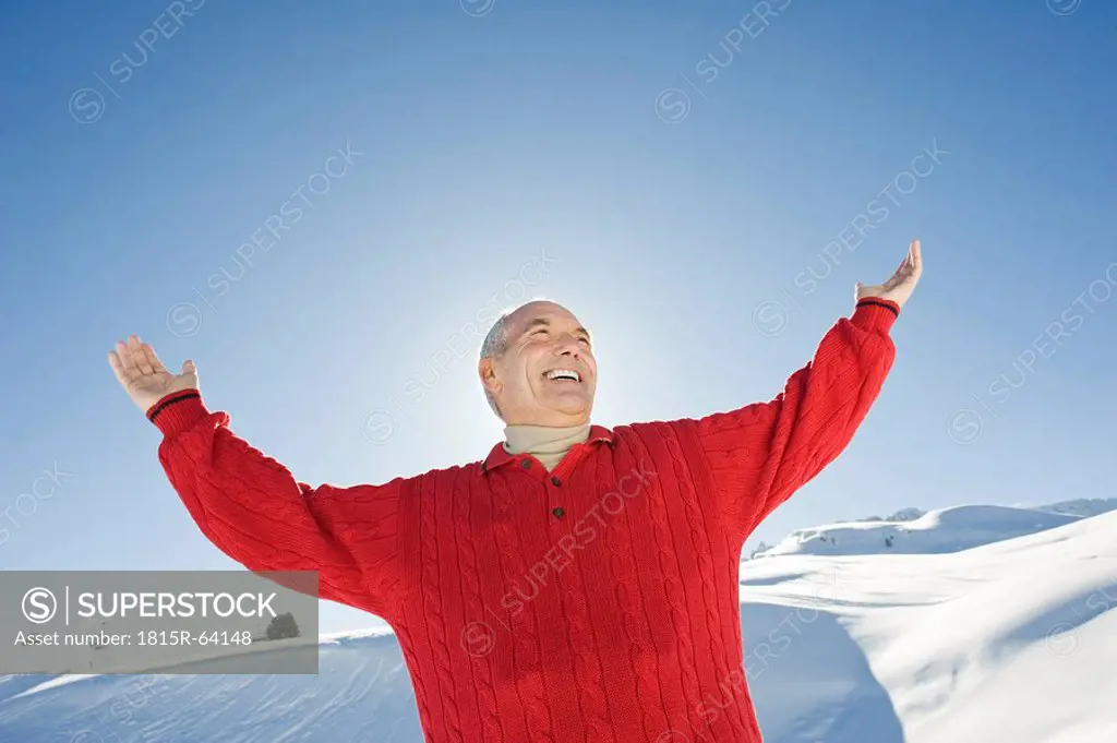 Italy, South Tyrol, Seiseralm, Senior man raising arms, smiling, portrait