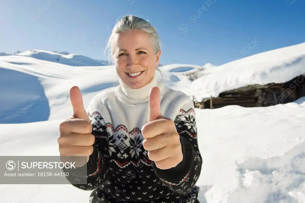 Italy, South Tyrol, Seiseralm, Senior woman thumbs up, smiling, portrait