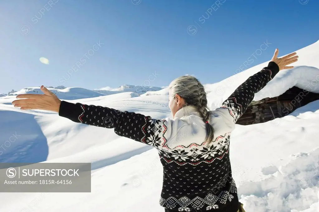 Italy, South Tyrol, Seiseralm, Senior woman, arms outstretched, rear view