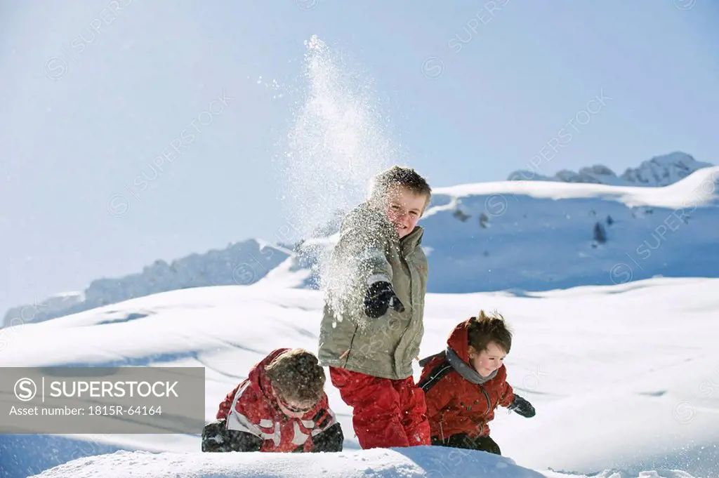 Italy, South Tyrol, Seiseralm, Children throwing snow in the air