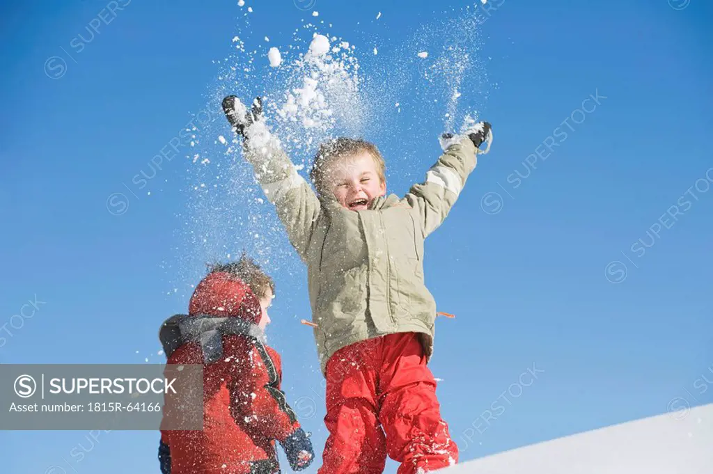Italy, South Tyrol, Seiseralm, Children throwing snow in the air
