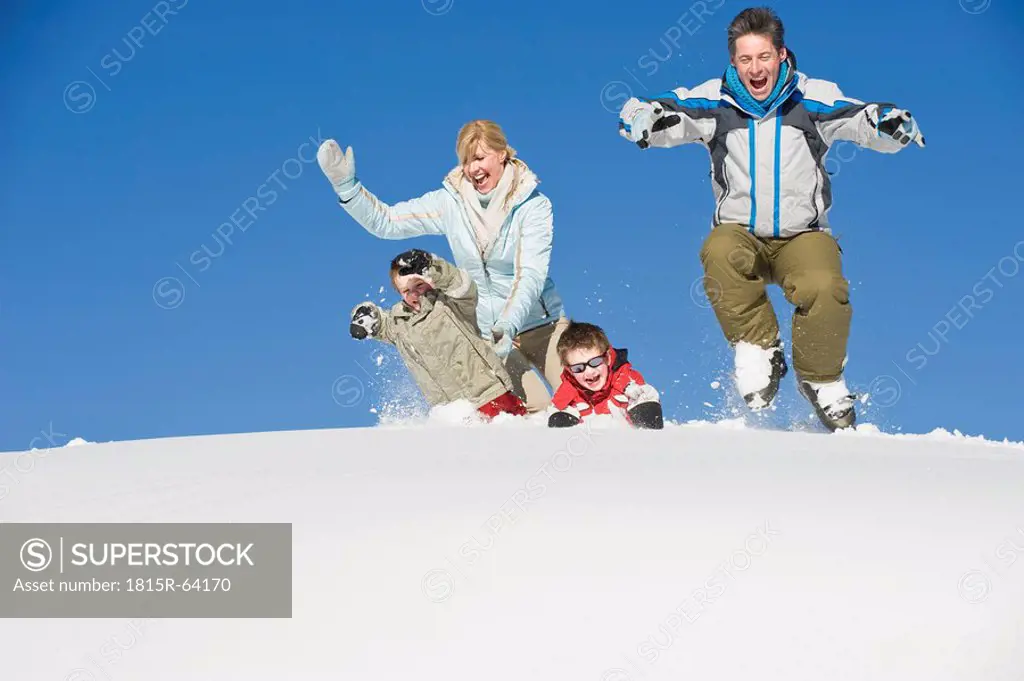 Italy, South Tyrol, Seiseralm, Family jumping in snow