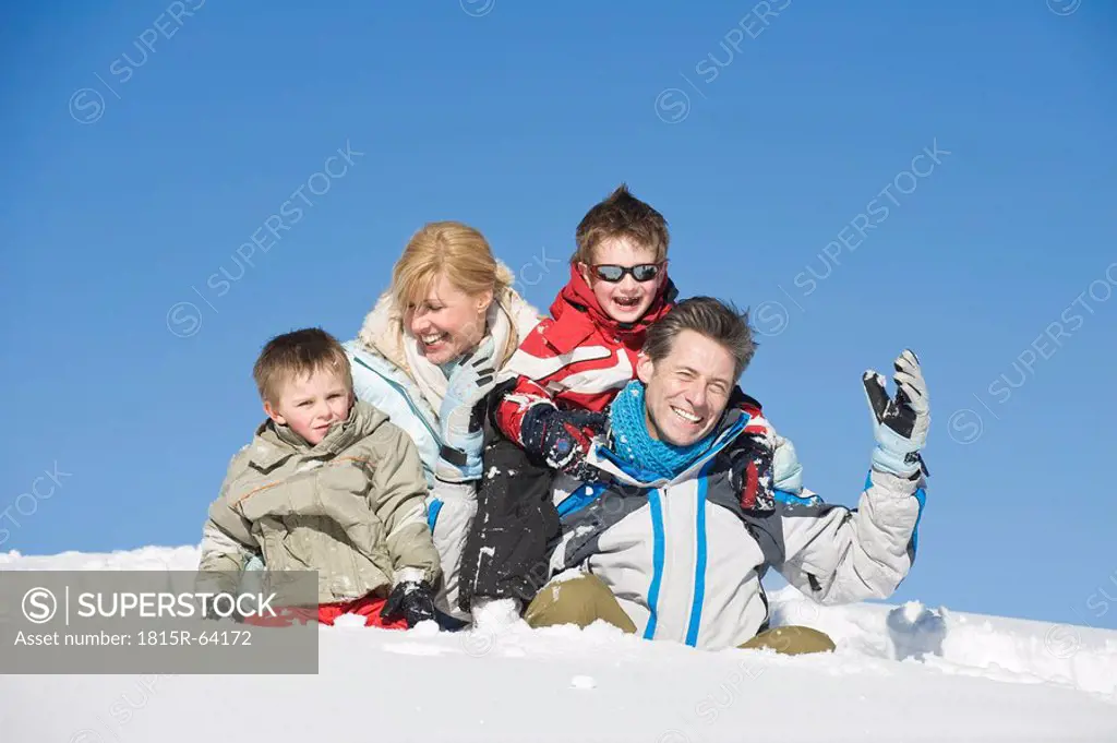Italy, South Tyrol, Seiseralm, Family sitting in snow, portrait