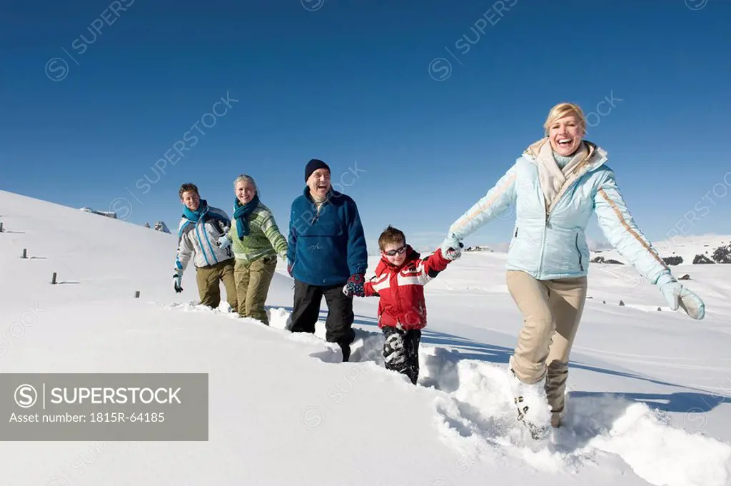 Italy, South Tyrol, Seiseralm, Family walking in snow