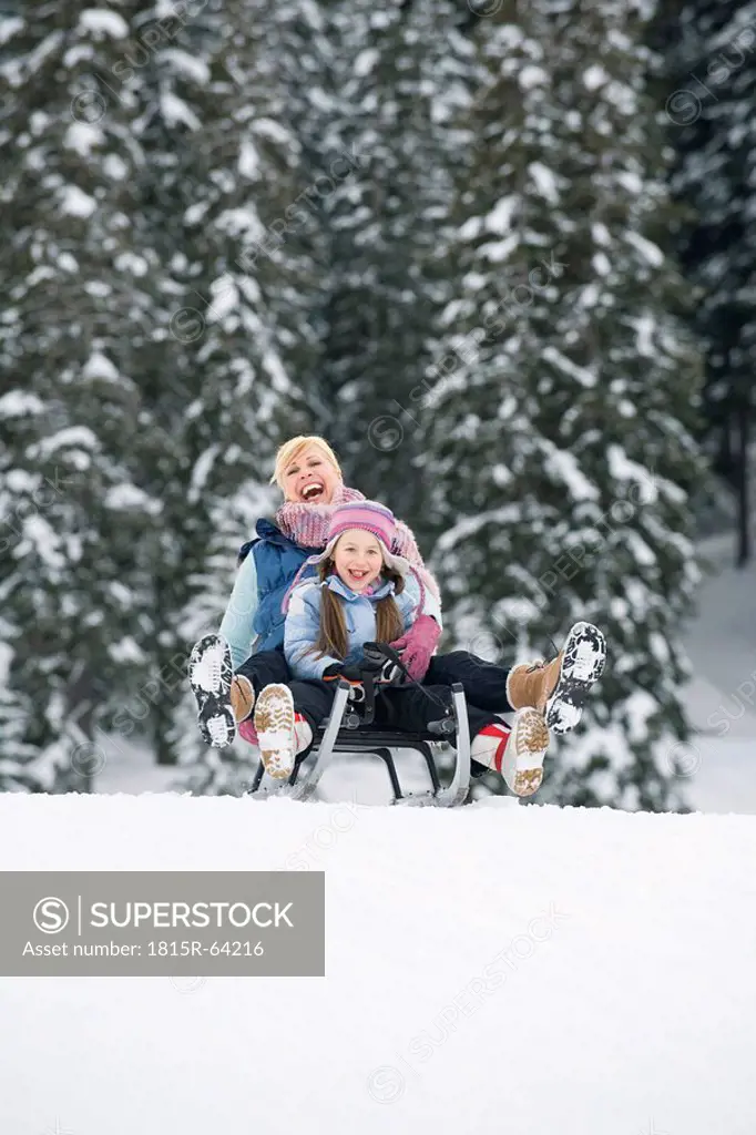 Italy, South Tyrol, Seiseralm, Mother and daughter 6_7 sledding downhill, laughing, portrait