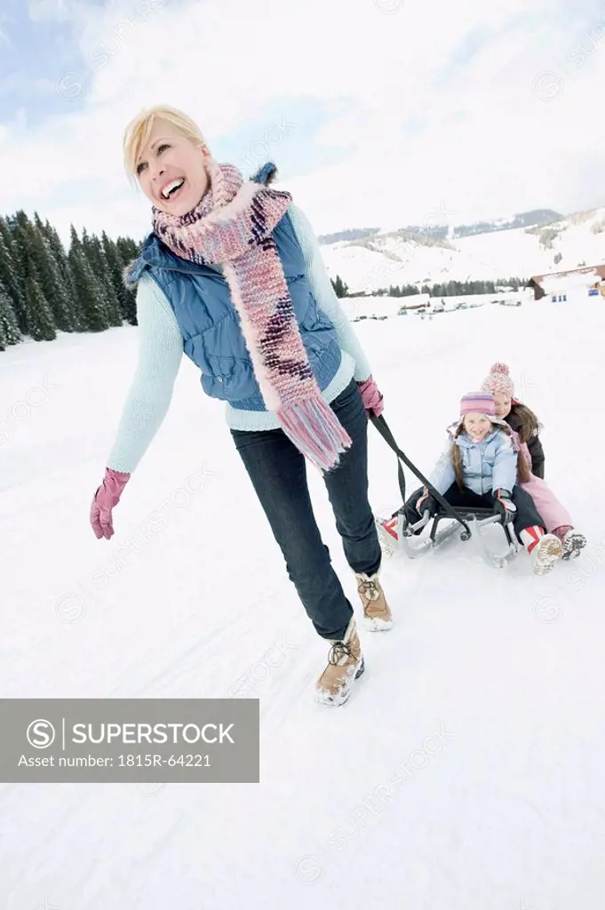 Italy, South Tyrol, Seiseralm, Woman pulling children 6_7 8_9 on sled