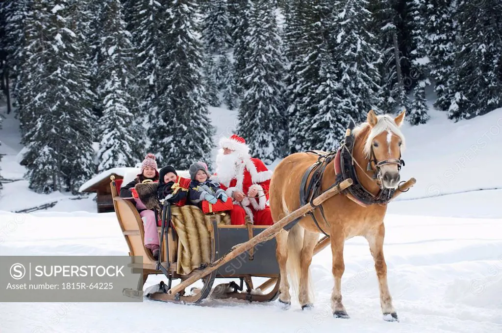 Italy, South Tyrol, Seiseralm, Santa Claus and children taking a sleigh ride