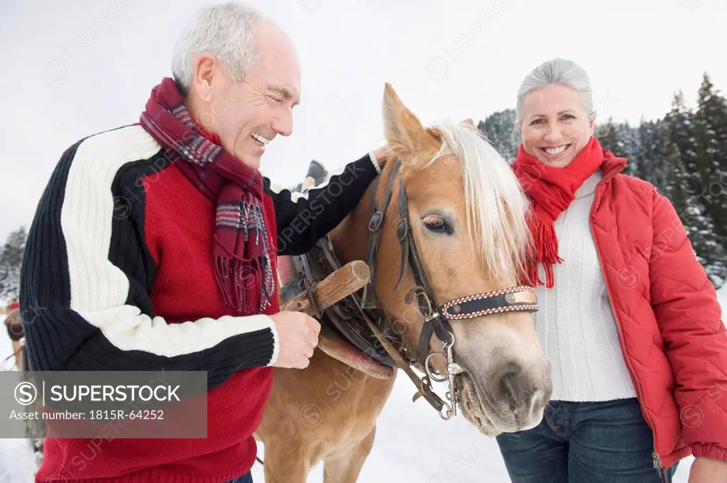 Italy, South Tyrol, Seiseralm, Senior couple standing by horse, smiling, portrait, close_up
