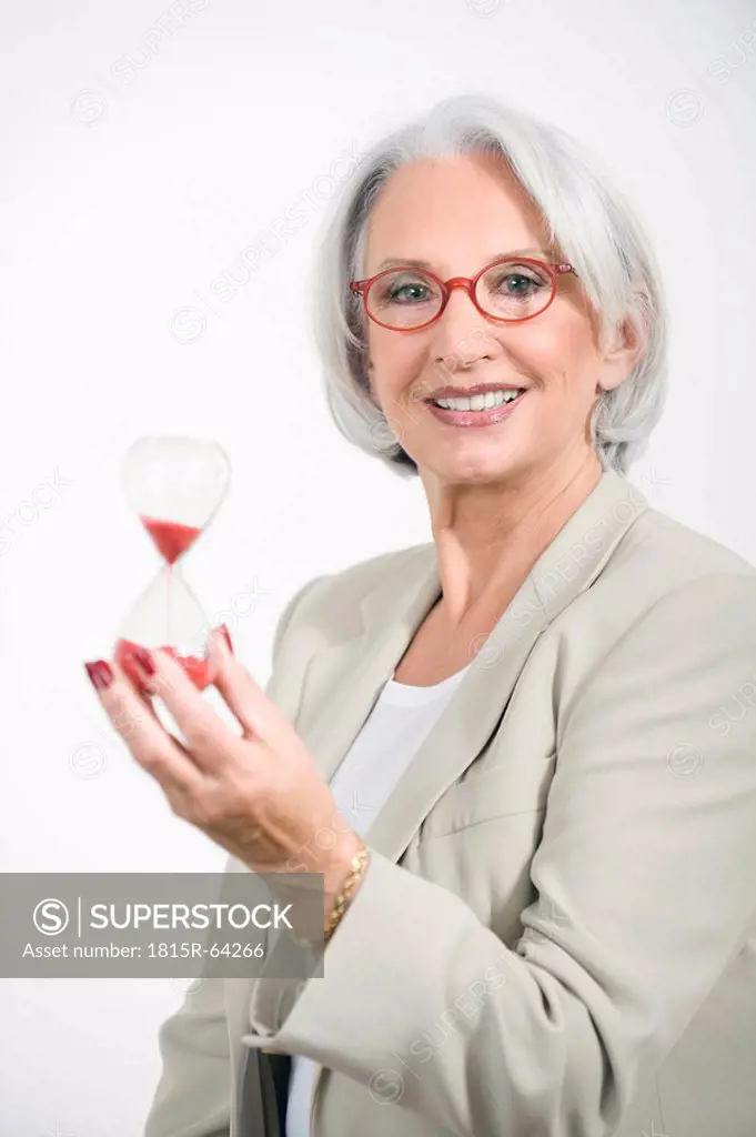 Senior Businesswoman holding sandglass, portrait