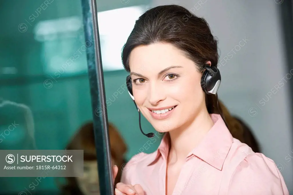 Germany, Munich, Woman with headset, colleague in background