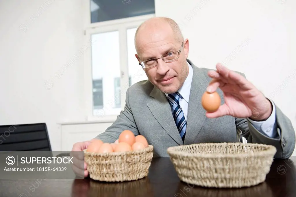 Germany, Munich, Businessman holding an egg, portrait