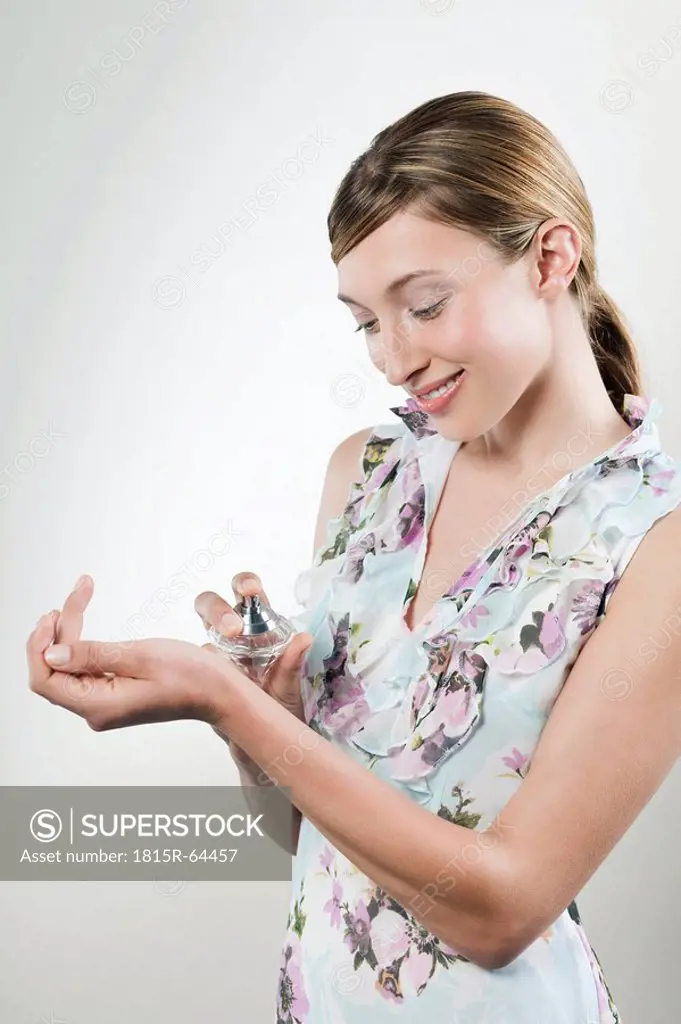 Young woman applying perfume on her wrist, portrait