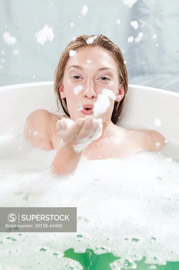 Young woman in bathtub, fooling about