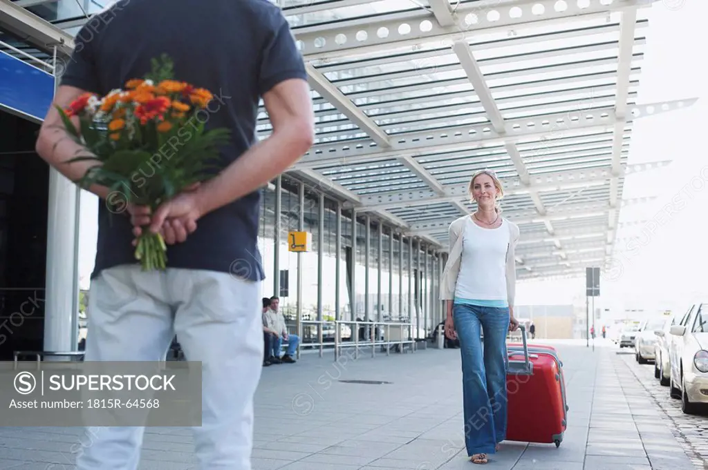 Germany, Leipzig_Halle, Airport, Woman with suitcase, Man holding flowers