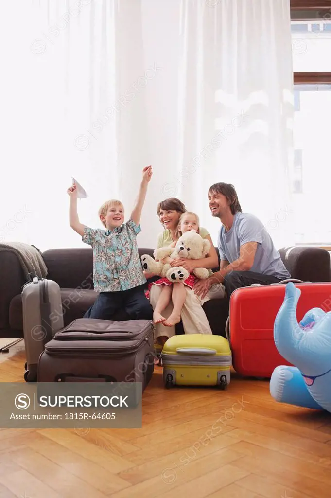 Germany, Leipzig, Family sitting on sofa, boy 8_9 holding paper plane, laughing