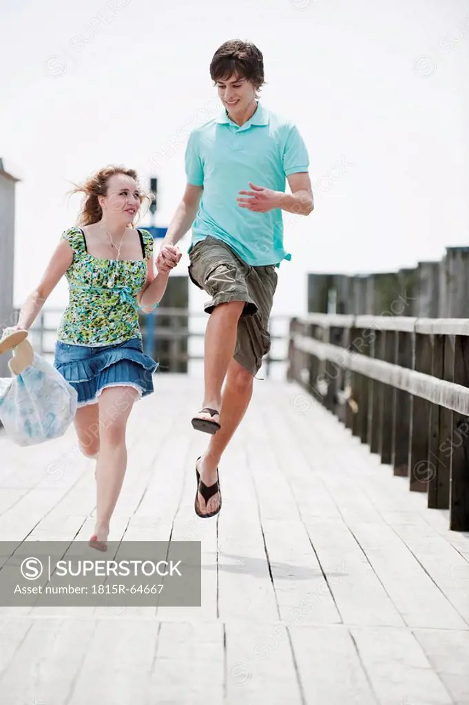 Germany, Bavaria, Ammersee, Young couple running on pier