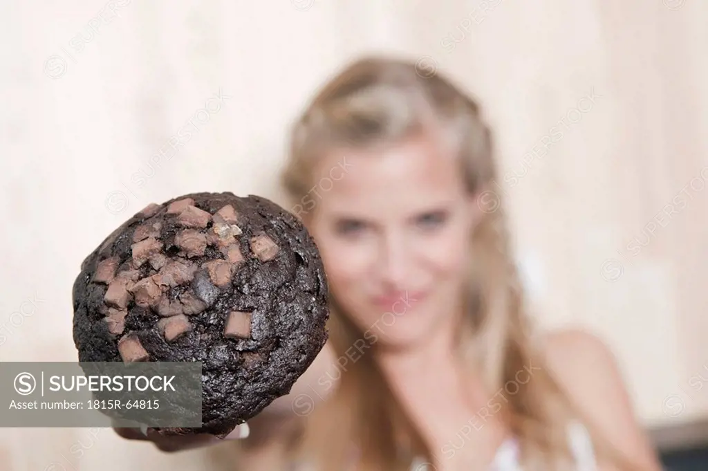 Germany, Cologne, Young woman holding cookie, close_up