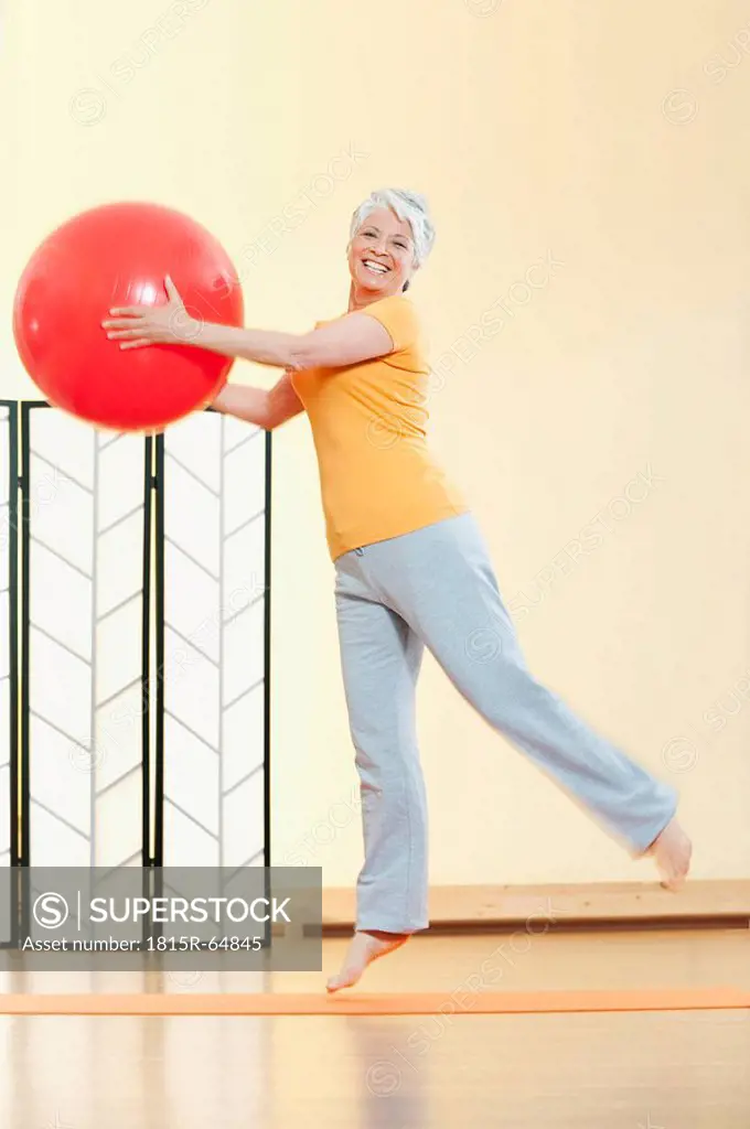 Senior woman holding gymnastic ball, portrait