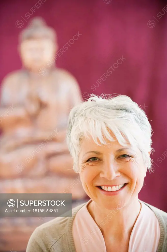 Portrait of a senior woman in background a buddha statue