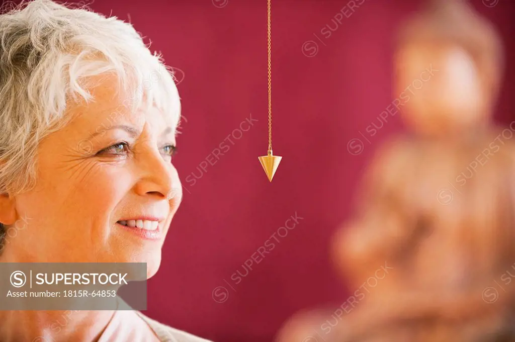 Portrait of a senior woman holding pendulum