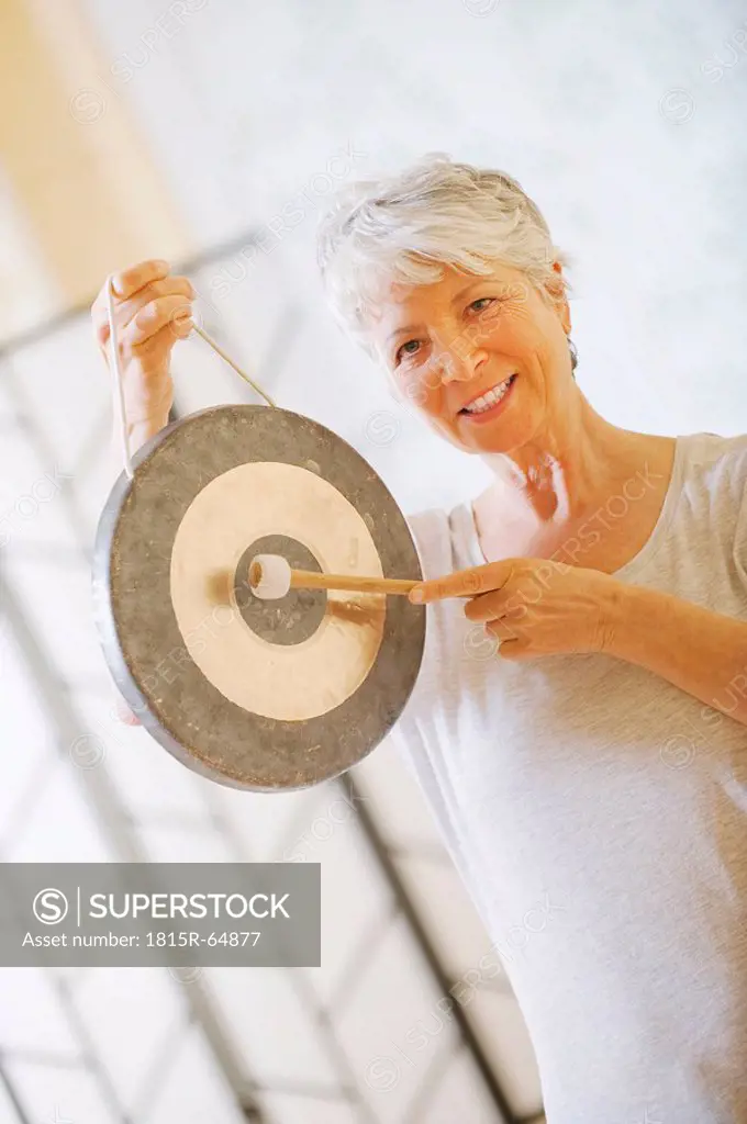 Senior woman holding gong, portrait