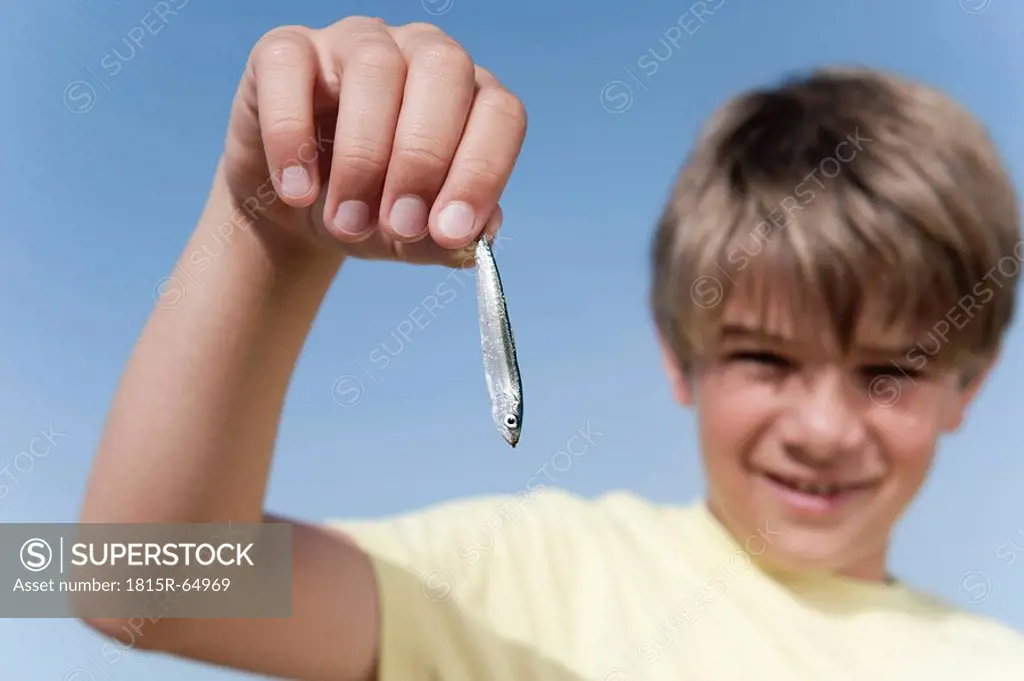 Boy 8_9 holding small fish, close_up