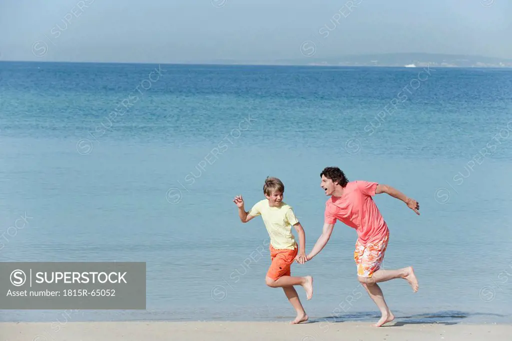 Spain, Mallorca, Father and son 8_9 running across beach