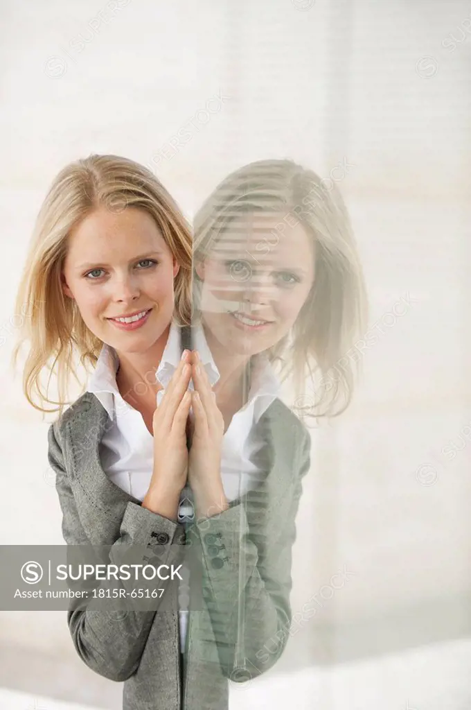 Businesswoman smiling, reflection in glass pane