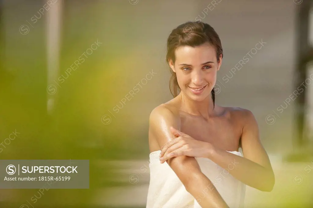 Young woman applying cream on arms