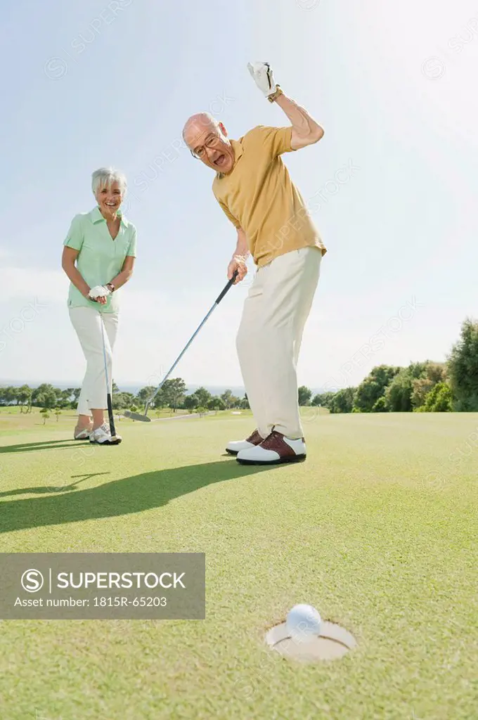 Spain, Mallorca, Senior couple on golf course, man cheering