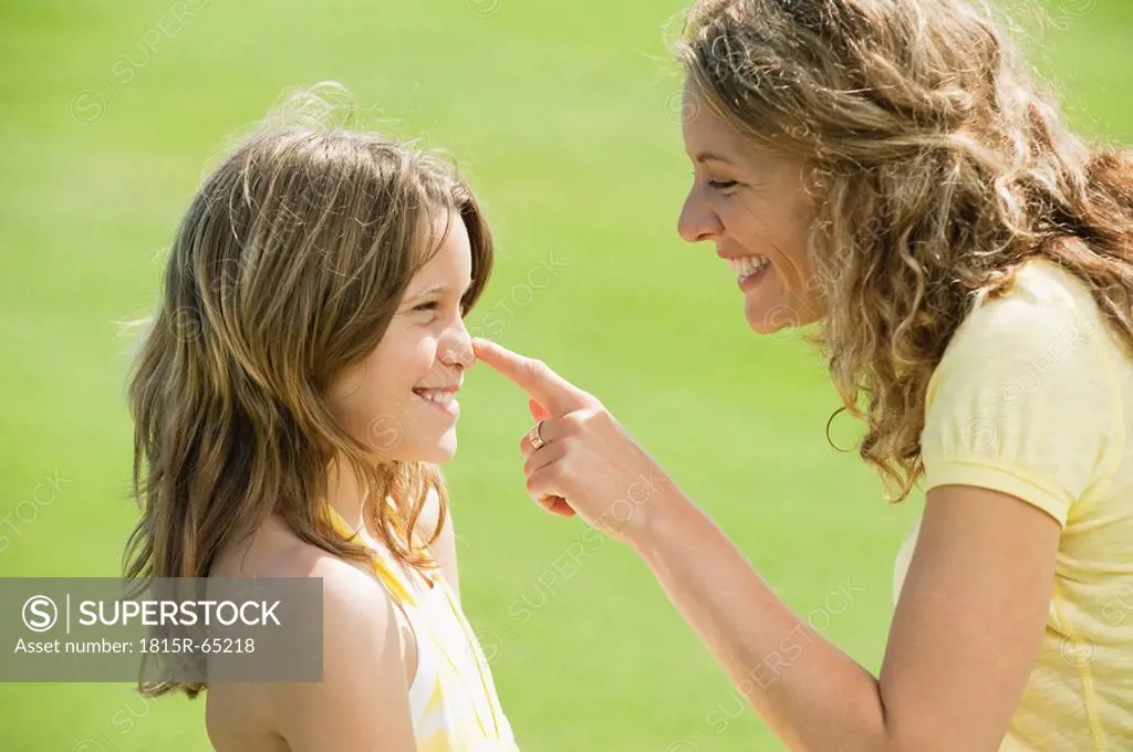 Spain, Mallorca, Mother touching daughter´s 10_11 nose, smiling, side view, portrait