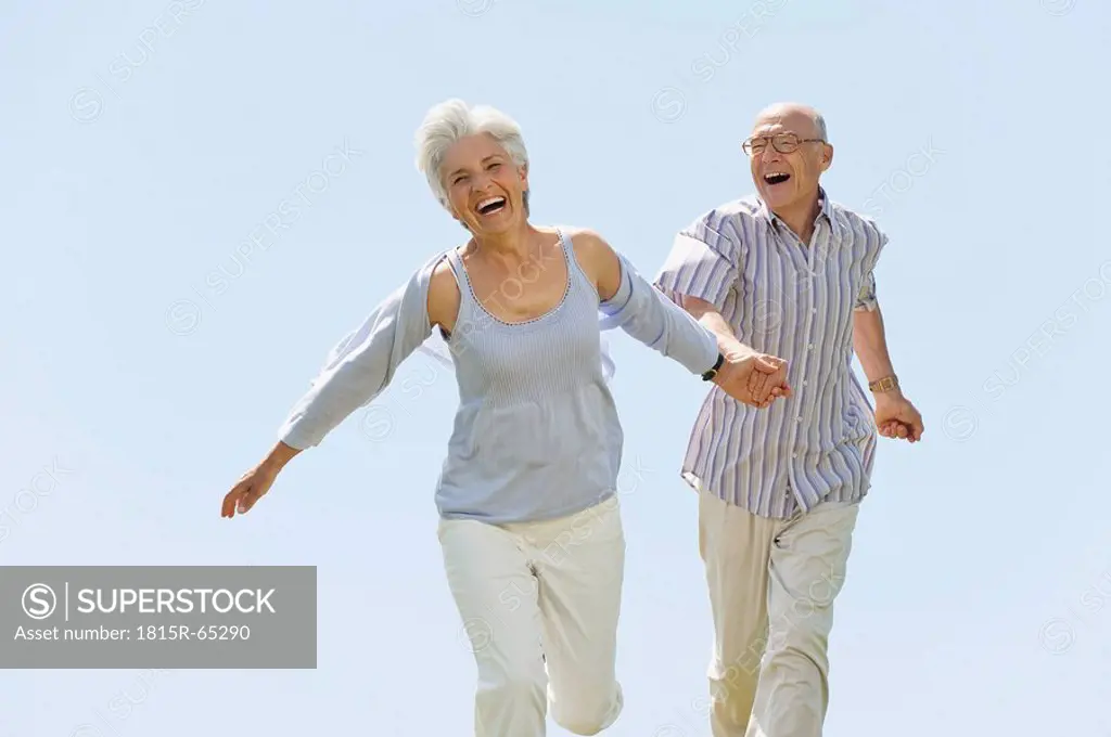 Senior couple running hand in hand, portrait