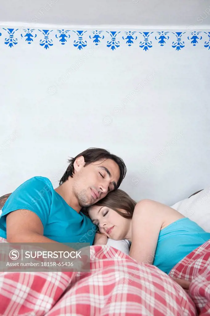 Germany, Bavaria, Young couple lying in bed