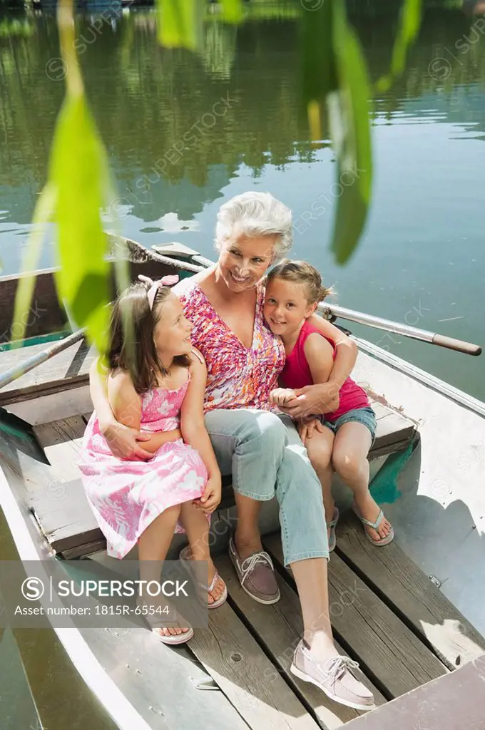 Italy, South Tyrol, Grandmother and grandchildren 6_7 8_9 sitting in rowing boat, elevated view, portrait