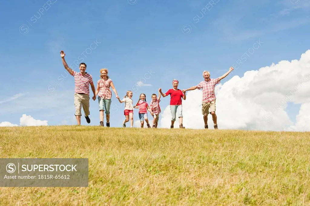 Italy, Seiseralm, Family walking in field, cheering