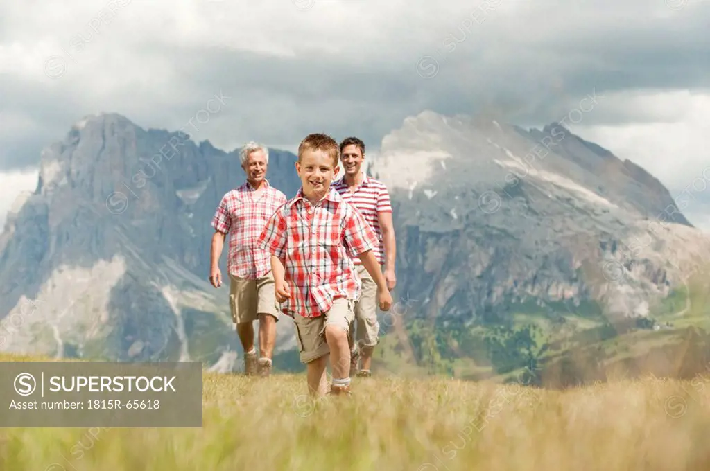 Italy, Seiseralm, Grandfather, Father and son 6_7 walking in meadow, smiling, portrait