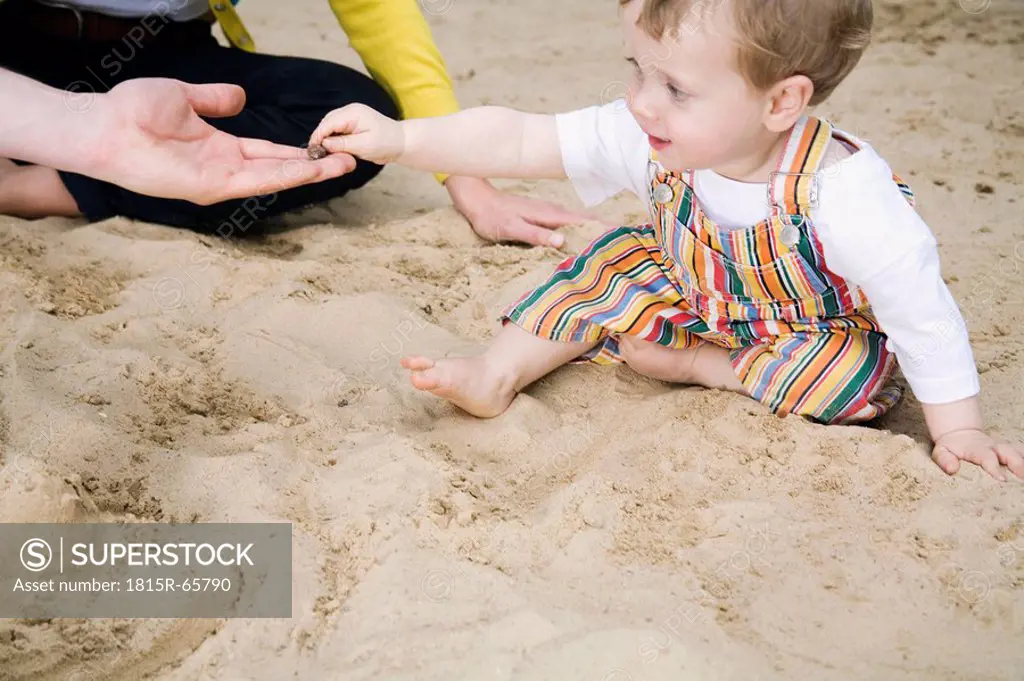 Germany, Berlin, Family and son 2_3 in sandbox, side view, portrait