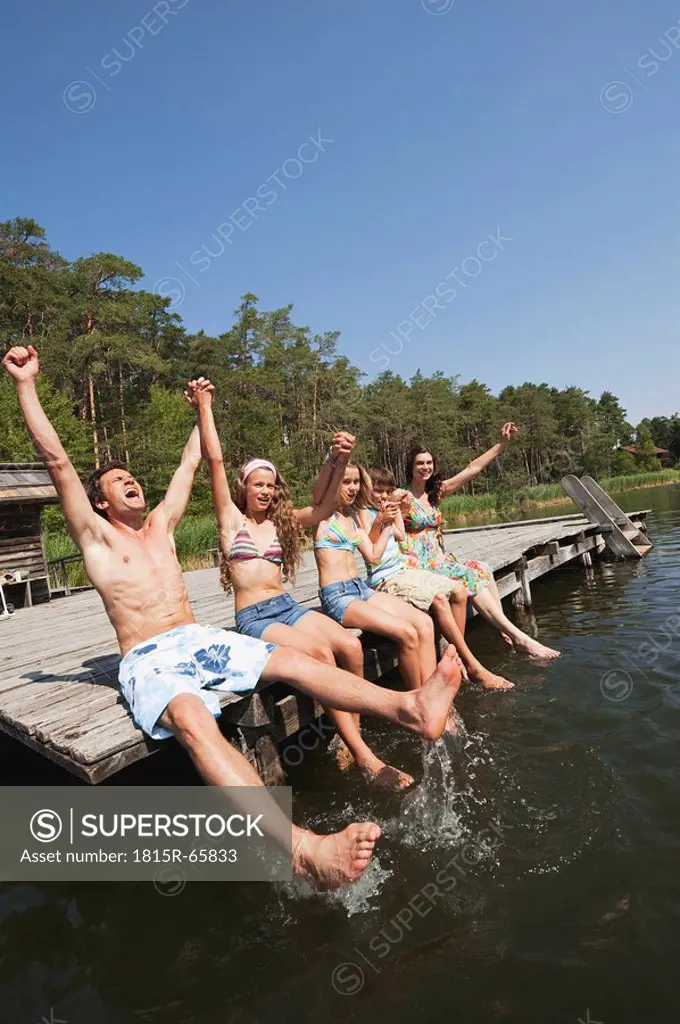 Italy, South Tyrol, Family sitting on jetty, cheering