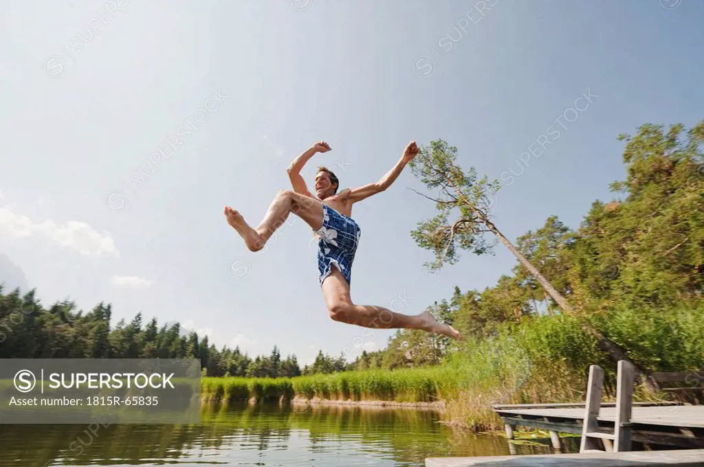 Italy, South Tyrol, Man jumping into lake