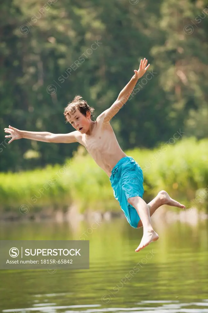 Italy, South Tyrol, Boy 10_11 jumping into lake