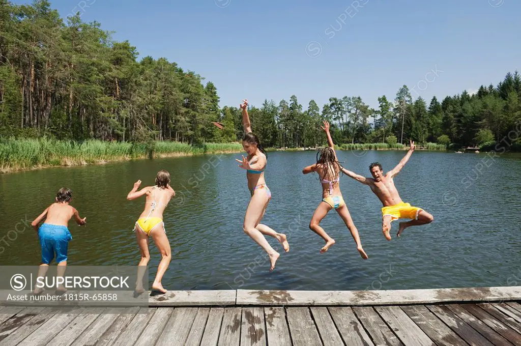Italy, South Tyrol, Family jumping into lake