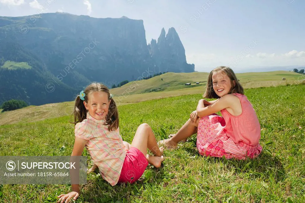 Italy, South Tyrol, Seiseralm,Two girls 6_7 10_11 sitting in meadow