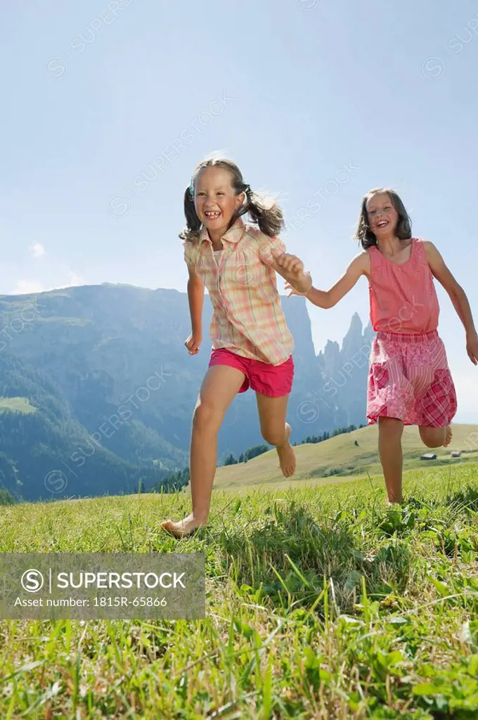 Italy, South Tyrol, Seiseralm, Two girls 6_7 10_11 running in field