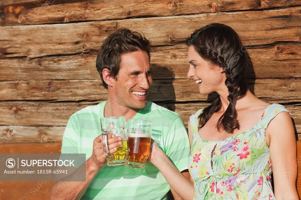 Italy, South Tyrol, Couple toasting with beer, laughing, portrait