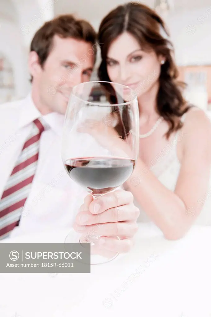 Couple in restaurant, man holding glass of red wine, portrait