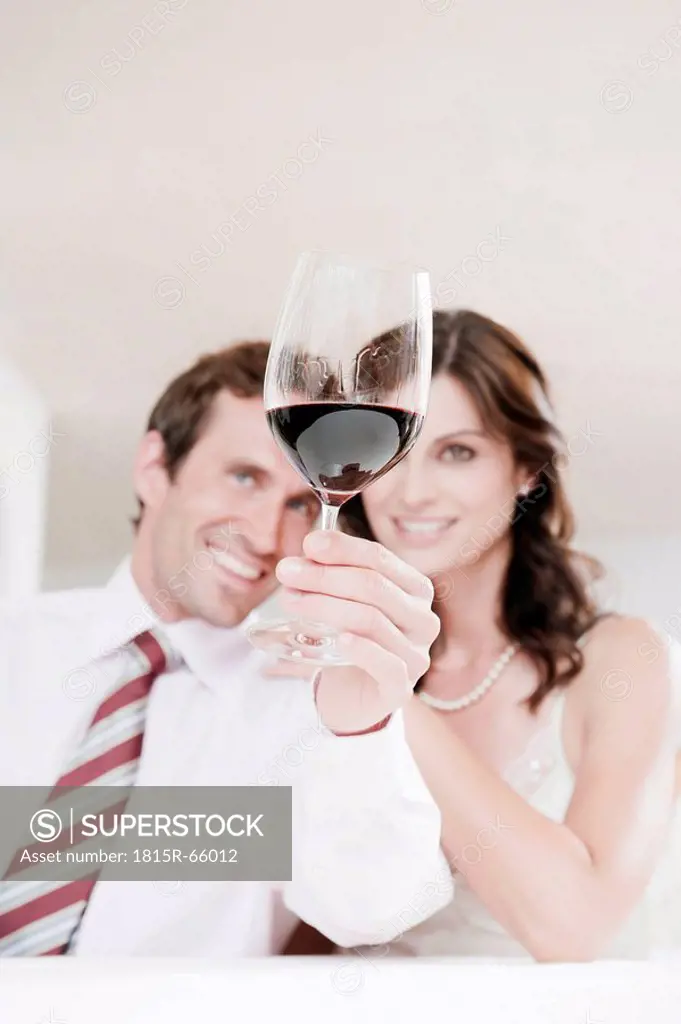 Couple in restaurant, man holding glass of red wine, portrait