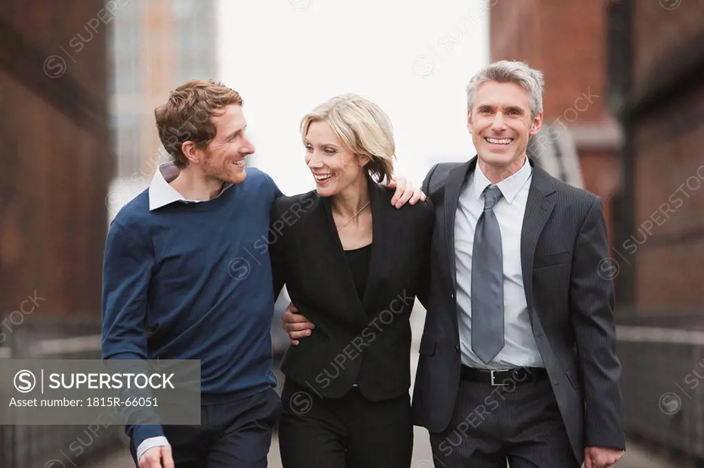 Germany, Hamburg, Three Business people walking side by side, smiling, portrait