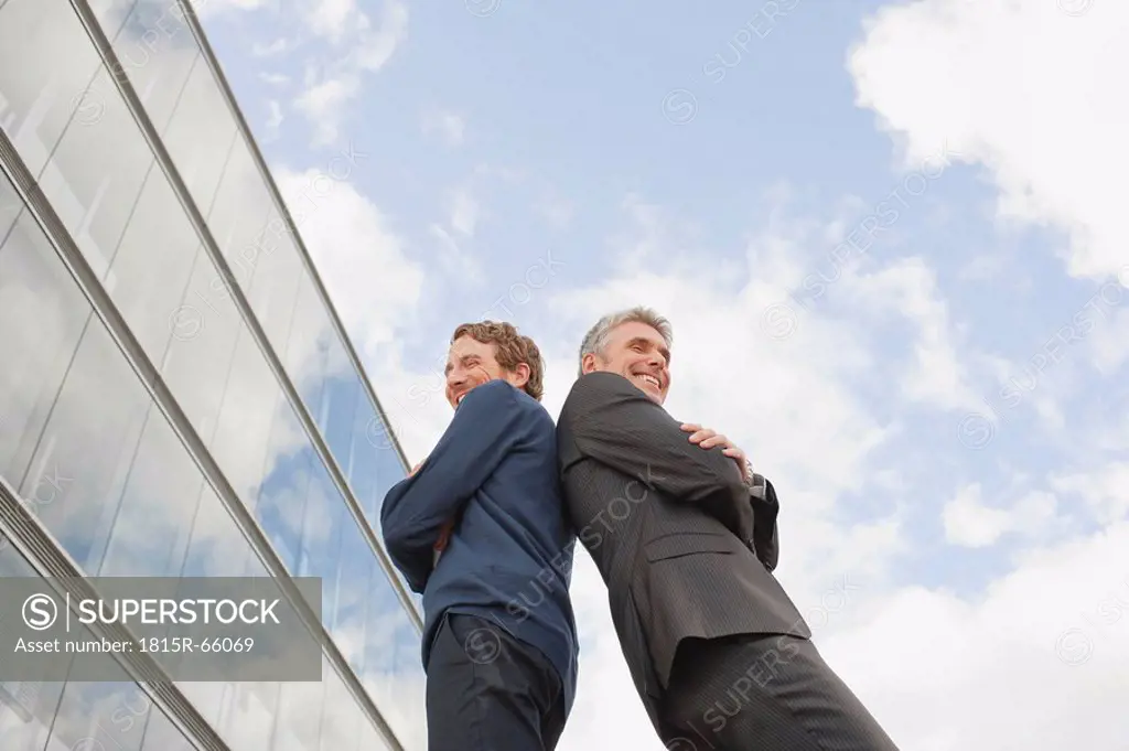 Germany, Hamburg, Two businessmen standing back to back, low angle view
