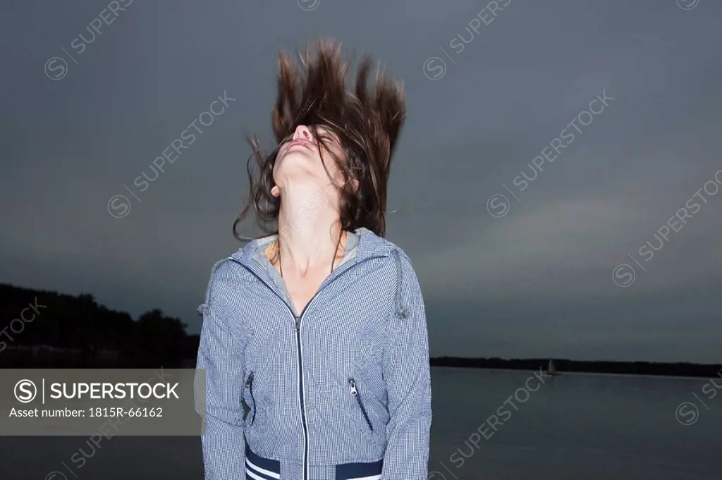 Germany, Berlin, Lake Wannsee, Young woman throwing head back, eyes closed