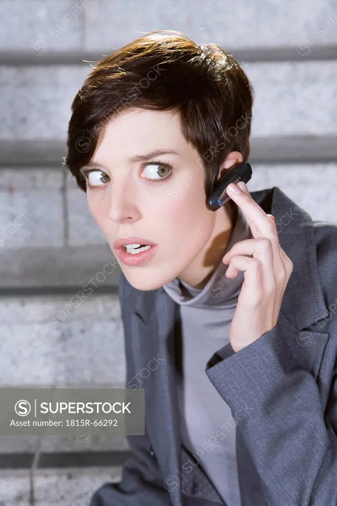Germany, Bavaria, Munich, Business woman wearing bluetooth headset, portrait, close_up